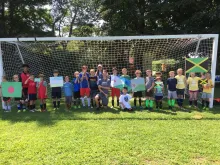Kids standing on the field posing in front of the goal
